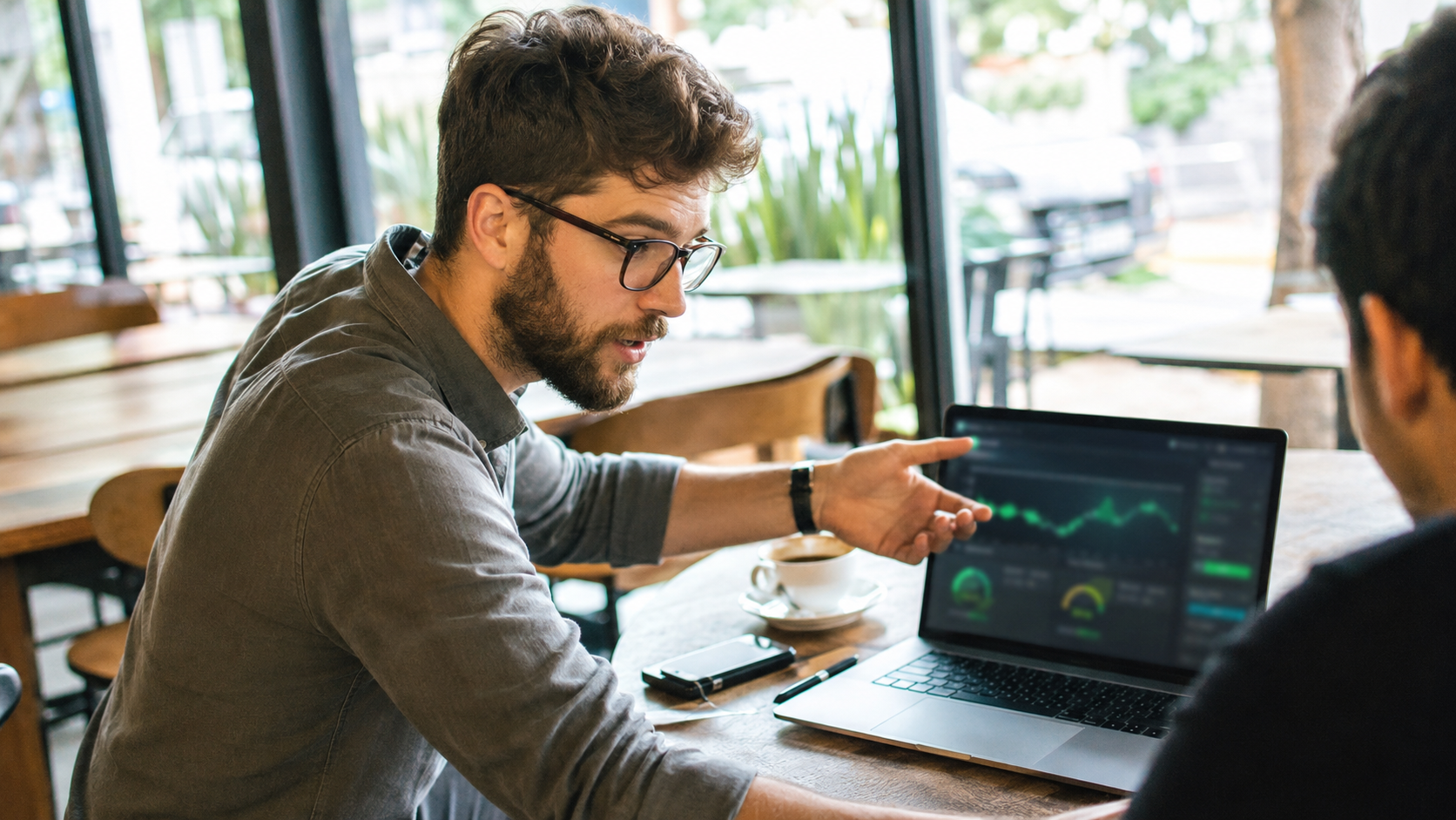 Especialista em tecnologia focado analisando métricas de performance no monitor em uma cafeteria clara